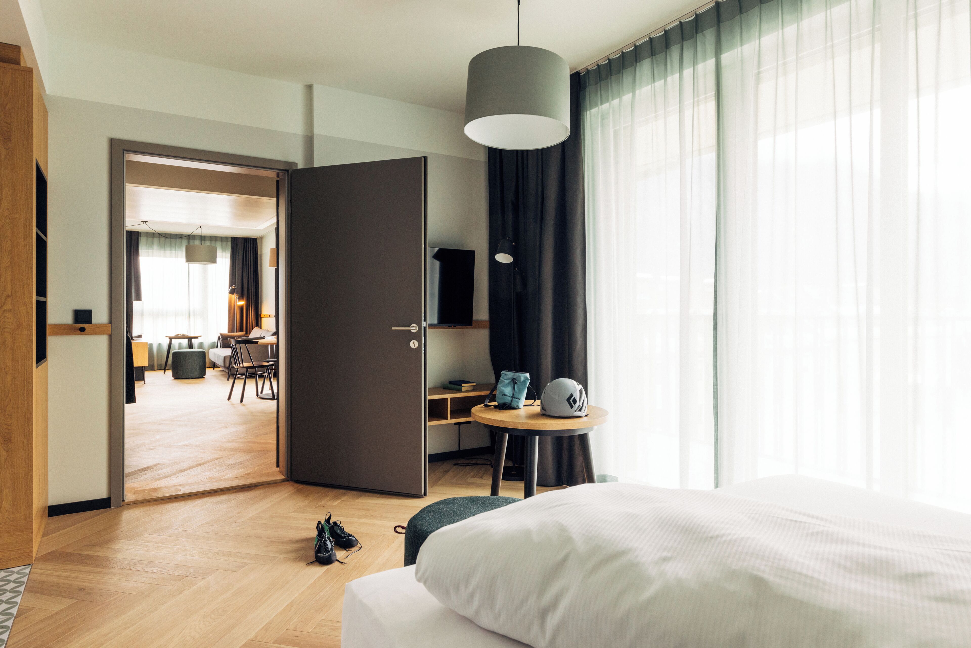 Et hotelværelse med seng, skrivebord, stol, lille bord og dør til spiseområde.