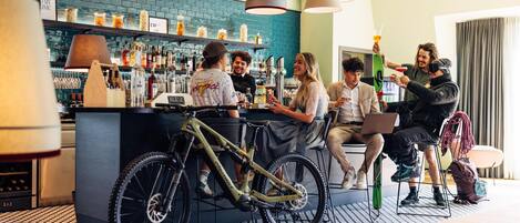 Zona de bar con mostrador, estantes con botellas y una bicicleta.