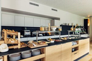 Una cocina moderna con encimera negra, armarios de madera y diversos alimentos y electrodomésticos.