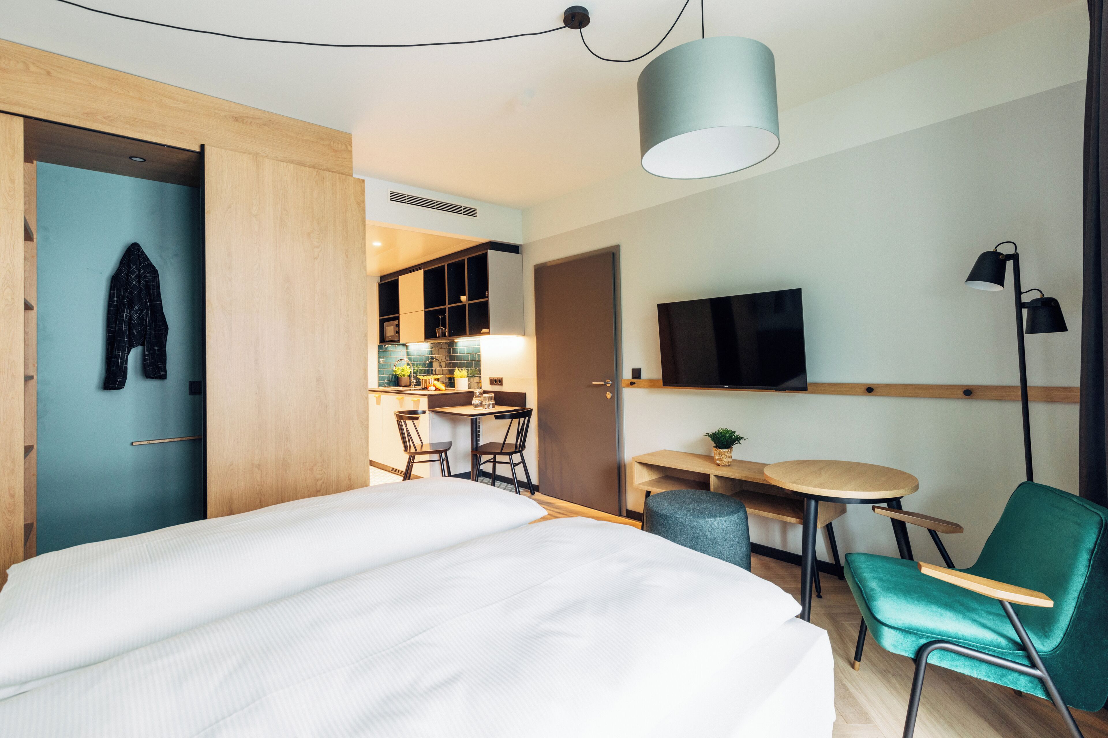 Una habitación de hotel moderna con una cama grande, un escritorio, una silla, un televisor y un área de comedor.