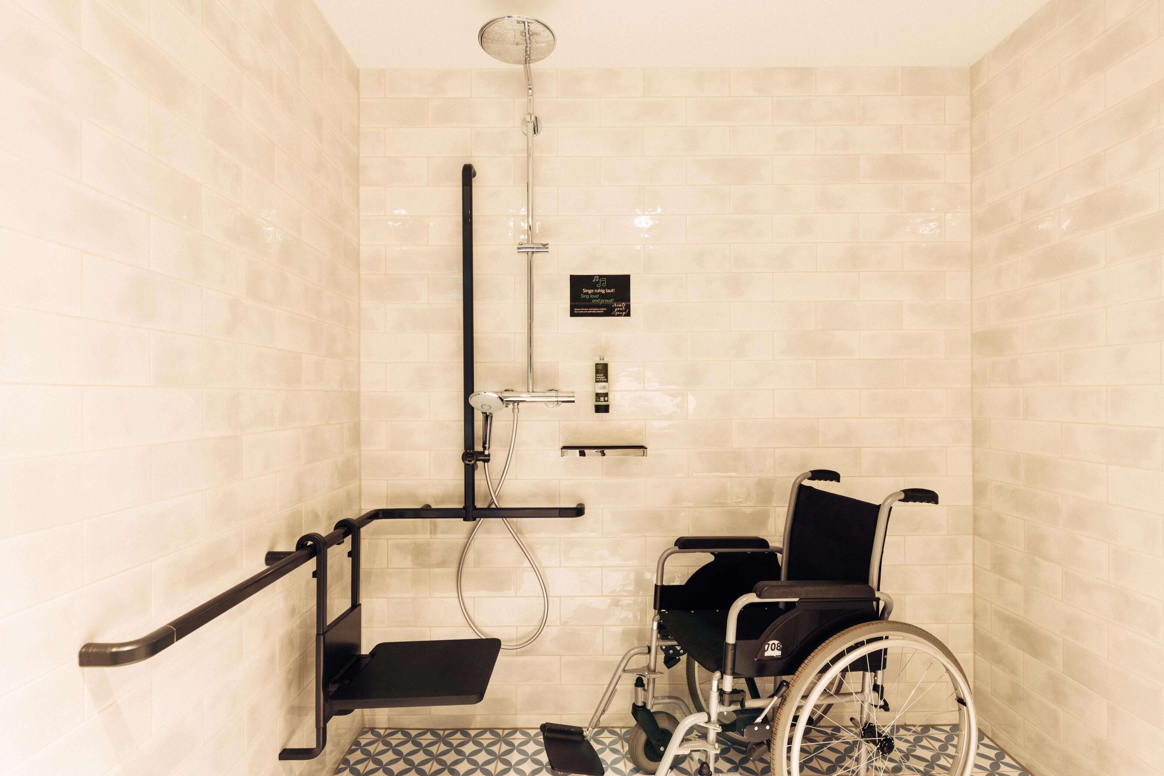 A wheelchair-accessible shower with a handrail, a bench, and a sign indicating it is a gender-neutral facility.