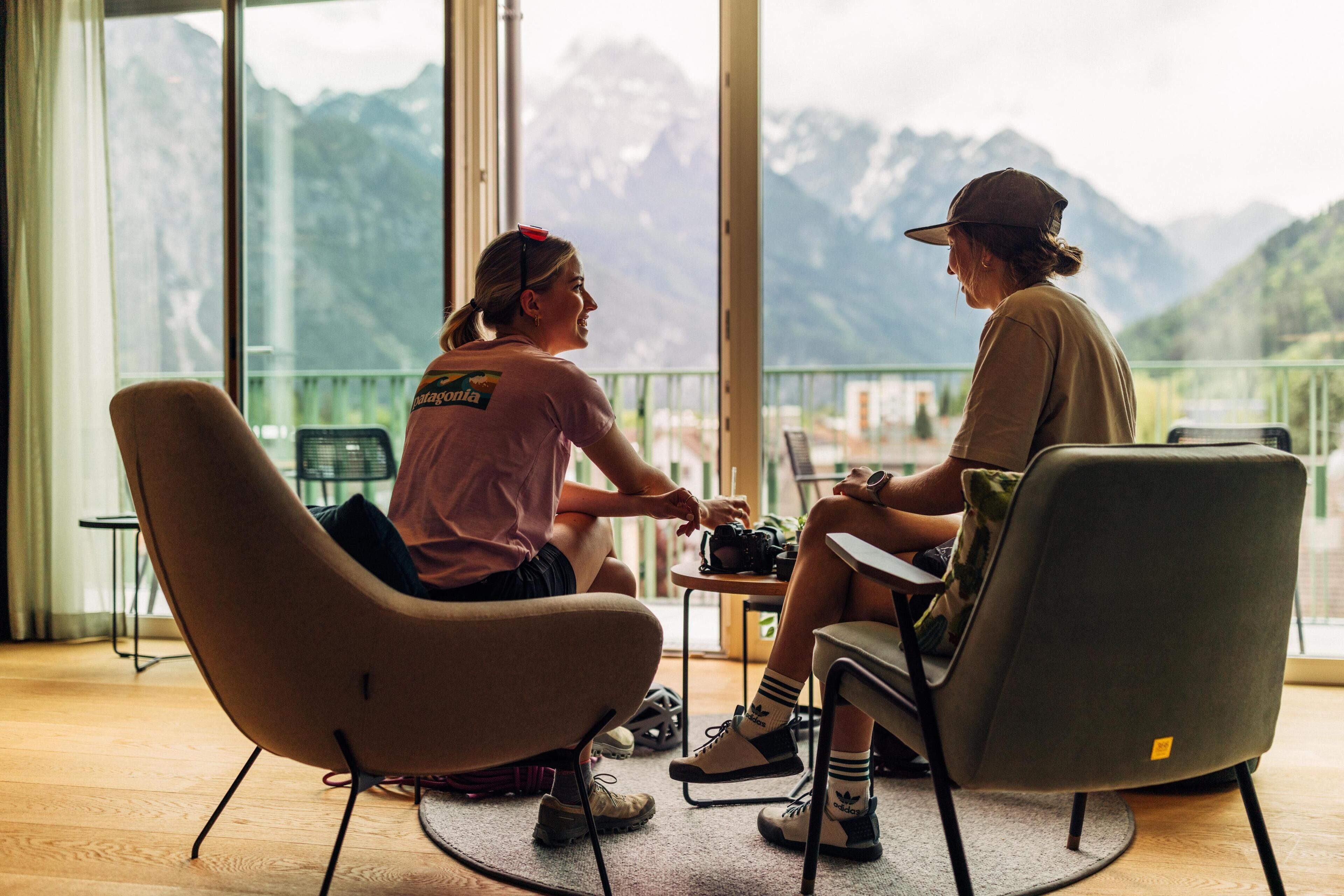 Two people seated at a table with a mountain view through large windows.