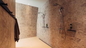 Een moderne badkamer met een douche, een handdoekhouder en een zeepdispenser.