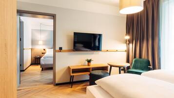 A hotel room with a bed, a desk, a chair, a television, and a lamp.