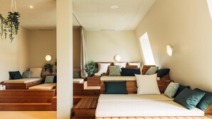 A modern, well-lit room with a wooden bed, a seating area with cushions, and a small table. - harry's home Lienz hotel & apartments (Lienz)