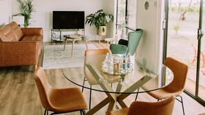 Un salon moderne avec une table à manger en verre, un canapé en cuir et un téléviseur à écran plat.