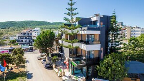 A modern multi-story building with balconies, a visible ATM, and a sign for a restaurant. - Hotel Joni Premium  (Ksamil)