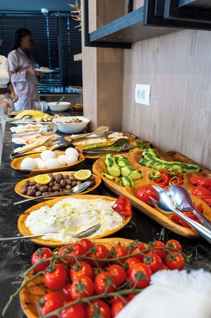Un buffet proposant une variété d’aliments, notamment des œufs, des légumes et des tomates.