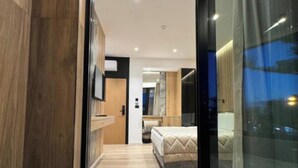 A modern bedroom with a large bed, wooden flooring, and a glass door leading to a balcony. - Hotel Joni Premium  (Ksamil)