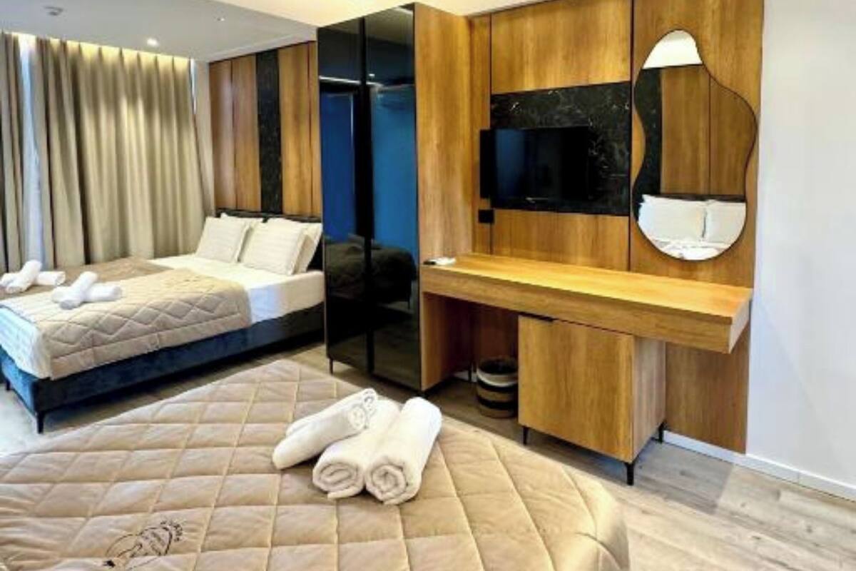 A modern hotel room with a large bed, a desk, a TV, and a mirror.