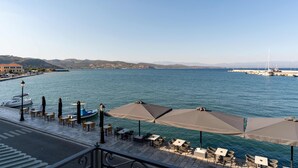 A waterfront restaurant with outdoor seating, a view of the sea, and a distant cityscape. - YeeOn Boutique Hotel, Gythio - Historic Hotels of Europe (East Mani)
