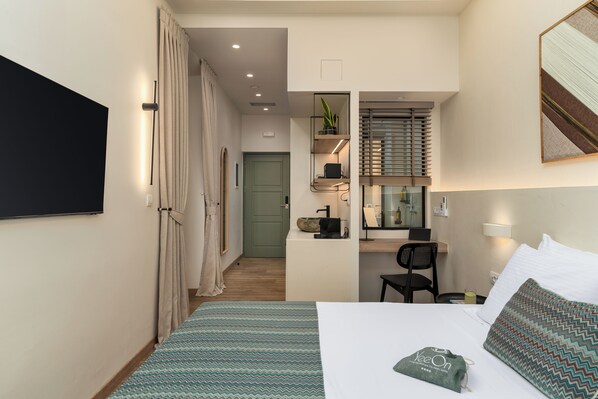 A compact hotel room with a bed, a desk, a chair, a mirror, and a TV. - YeeOn Boutique Hotel, Gythio - Historic Hotels of Europe (East Mani)