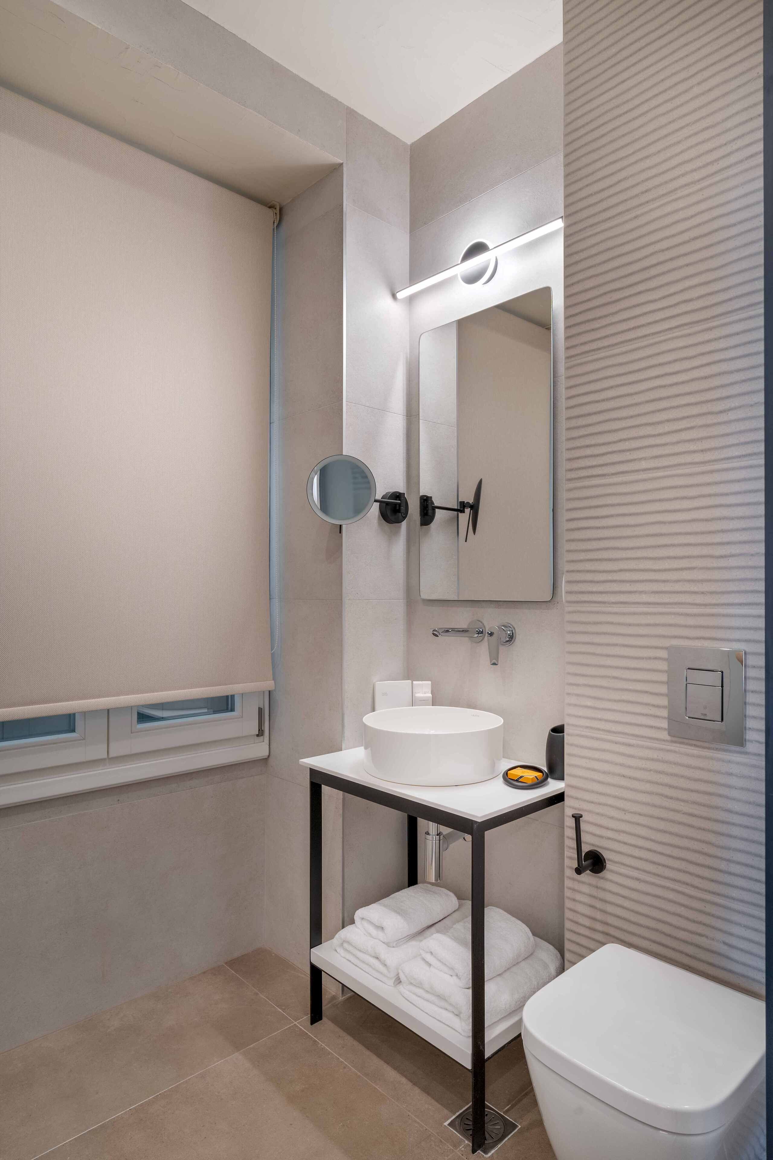 Un baño moderno con un lavabo blanco, un espejo y un inodoro.