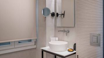 Un baño moderno con un lavabo blanco, un espejo y un inodoro.