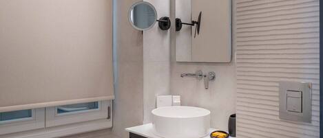 A modern bathroom with a white sink, a mirror, and a toilet.