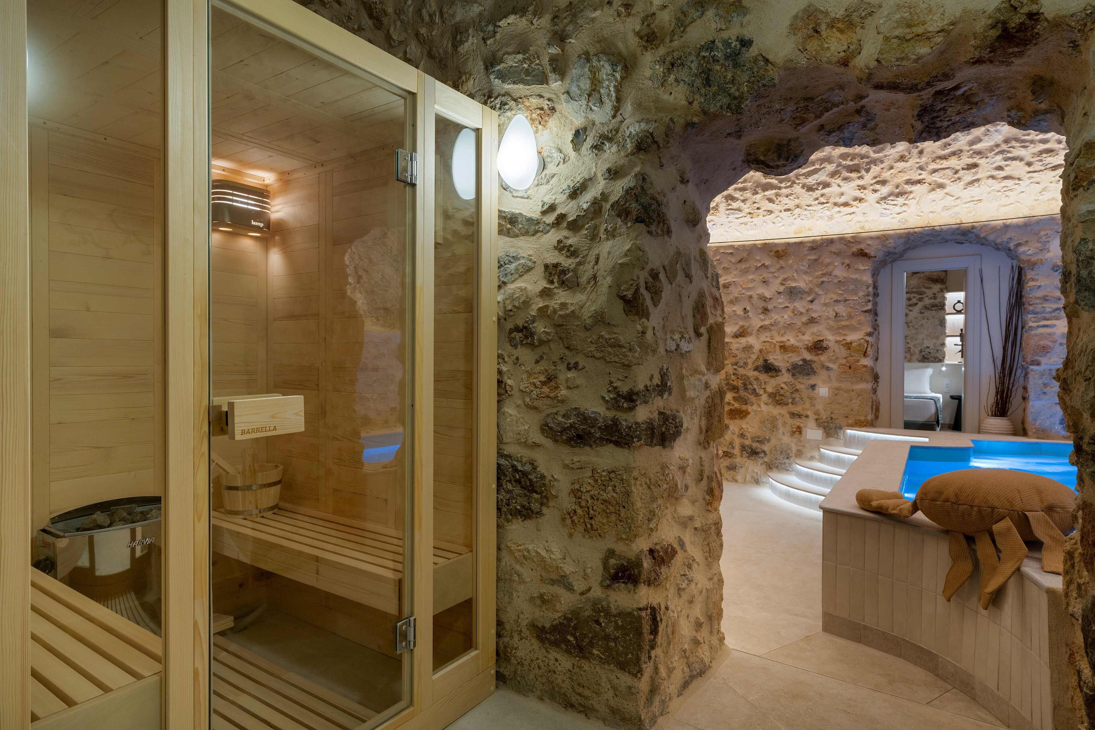 A stone-walled sauna room with a wooden bench and a towel rack.