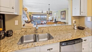 A kitchen with granite countertops, a double sink, and a dishwasher.