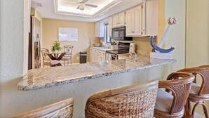 A kitchen with a central island, white cabinets, a microwave, and a ceiling fan.