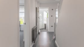 En smal gang med en radiator, en dør der fører til et andet rum og et vindue med udsigt ud