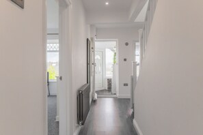 A narrow hallway with a radiator, a door leading to another room, and a window with a view of the outside.