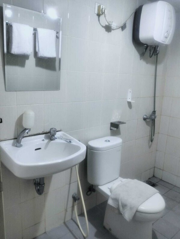 A small, clean bathroom with a white sink, toilet, and shower.