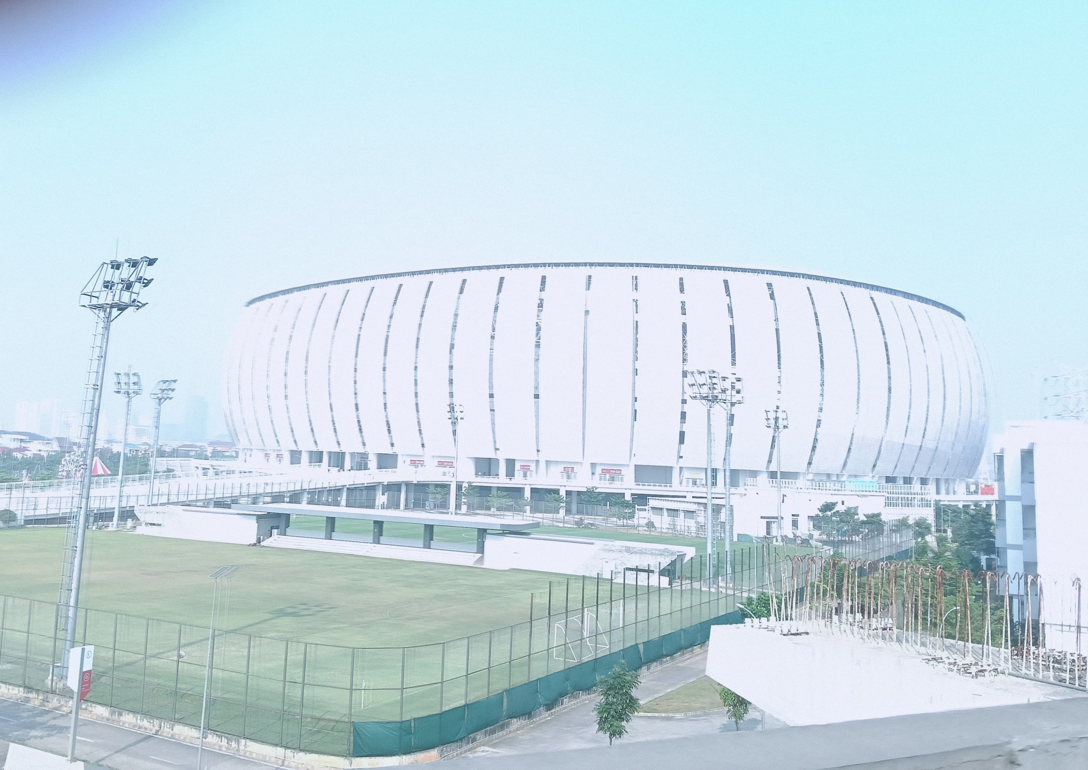Ein Stadion mit einer großen, runden Struktur in der Mitte, umgeben von einem eingezäunten Bereich und weiteren Gebäuden.