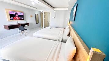 Habitación de hotel con dos camas, televisión, escritorio y una silla.