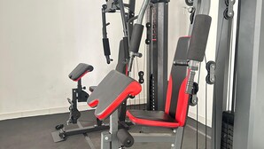 A gym with a squat rack, bench press, and various weight machines. - IZI COZI HOTEL KEMAYORAN  (Jakarta)