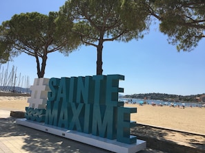 A large '#SAINTE MAXIME' sign in a coastal area with a beach and sailboats in the background. - Apartment du Levant 3-star 50m beach 1 bedroom private parking Bastide du Levant (Sainte-Maxime)