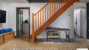 A staircase leading to a second floor, a small table with toys, a television on the wall, and a patterned rug on the floor.