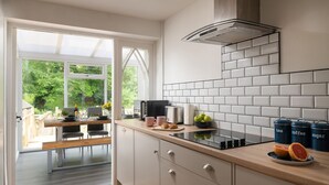 Una cocina moderna con armarios blancos, encimera negra y vistas a un jardín por la puerta abierta.