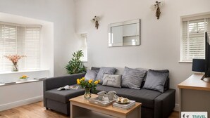 A modern living room with a grey sofa, a wooden coffee table, and a large mirror on the wall. - Katie`s Cottage and Hot Tub  Snowdon 20mins drive (Snowdonia & North Wales)