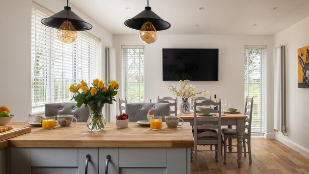 A modern kitchen with a central island, pendant lighting, and a dining area with a wooden table and chairs. - Katie`s Cottage and Hot Tub  Snowdon 20mins drive (Snowdonia & North Wales)