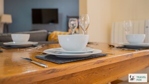 Una mesa de comedor servida con cuencos y platos blancos, un cuchillo y copas de vino.