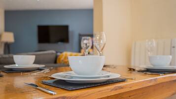 A dining table set with white bowls and plates, a knife, and wine glasses.