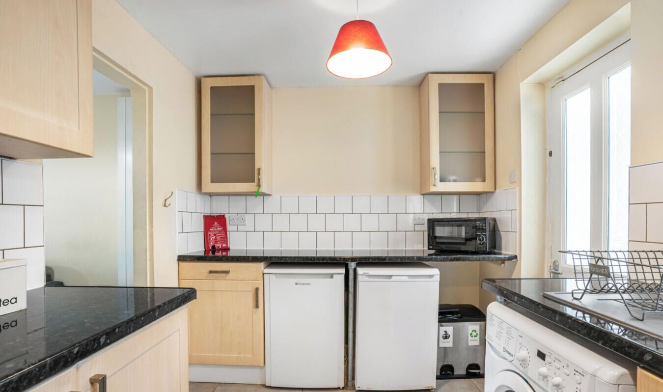 Een kleine keuken met een magnetron, twee koelkasten en een wasbak.