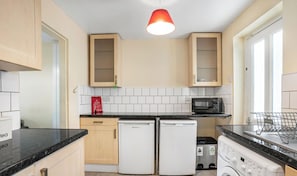 A compact kitchen with a microwave, two refrigerators, and a sink.
