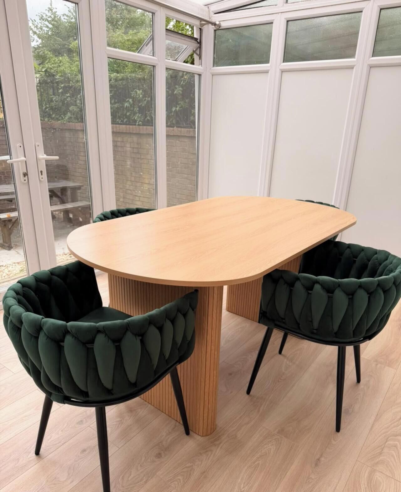 Una mesa de comedor con cuatro sillas, una puerta de vidrio y vistas al exterior.