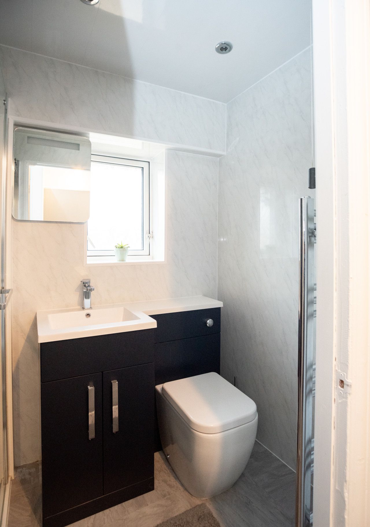 Une salle de bain moderne avec un lavabo blanc, des meubles sombres et des toilettes.