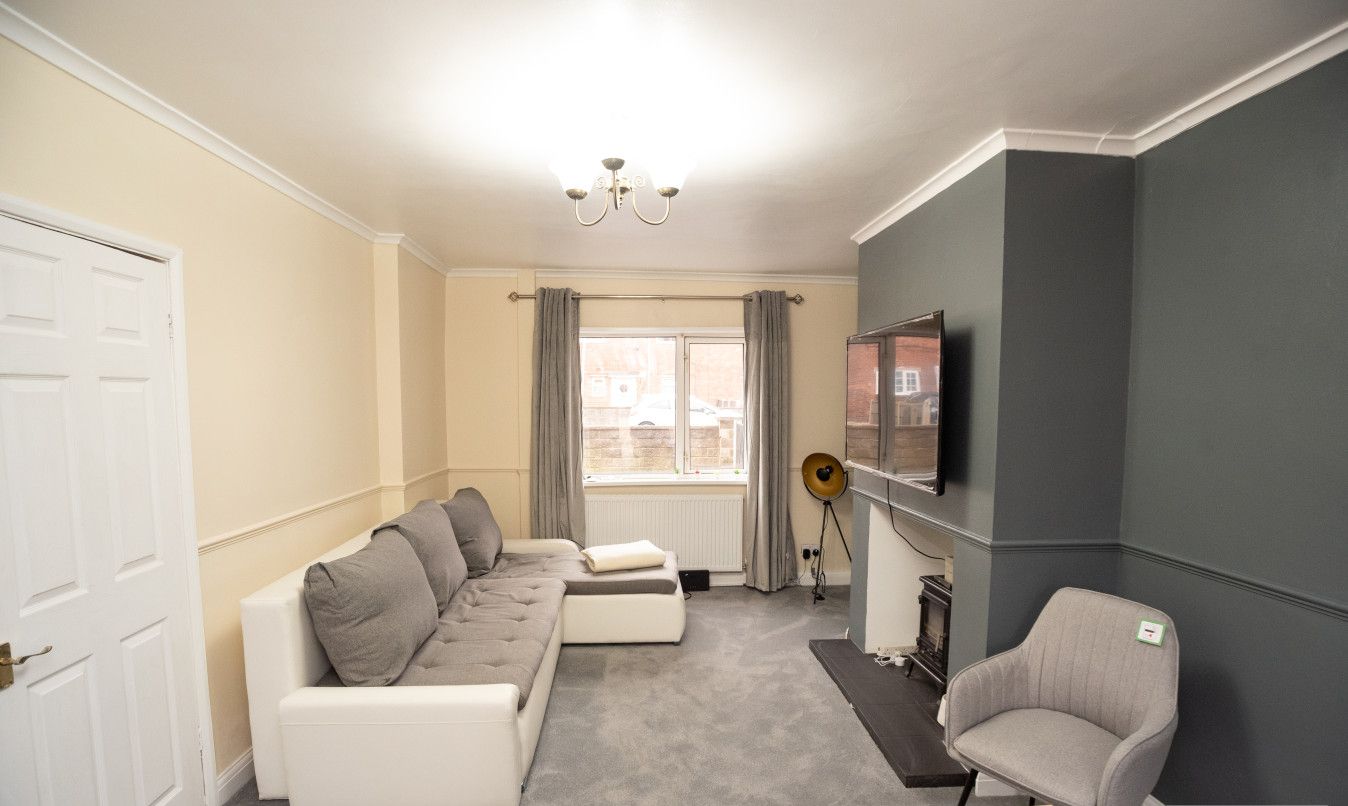 A living room with a sofa set, a television, a fireplace, and a chair.