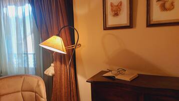 Una habitación con un sofá, una lámpara, un tocador y dos cuadros en la pared.