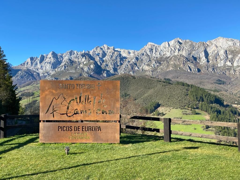 A sign with 'Santo Topiri 2' and 'Picos de Europa' written on it, set against a mountainous backdrop.