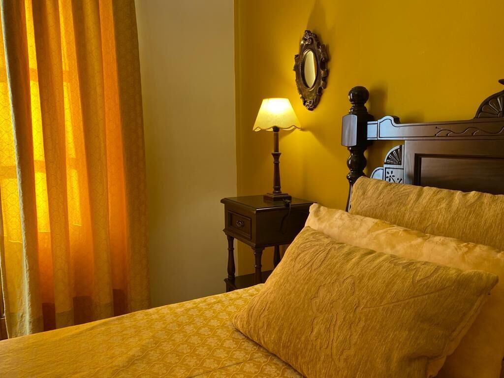 A hotel room with a bed, a nightstand with a lamp, and a mirror on the wall.