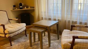 Un salon chaleureux avec une table basse en bois, deux fauteuils, une petite table et un radiateur.