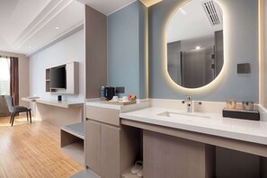 Une salle de bain moderne avec un grand miroir, un lavabo intégré et un téléviseur à écran plat fixé au mur.