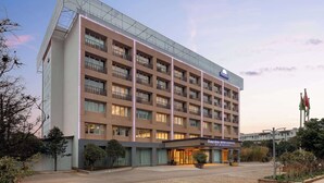 A multi-story hotel with a modern design, featuring a prominent glass facade and a flat roof. - Days Inn by Wyndham Kunming Airport Economic Zone (Kunming)