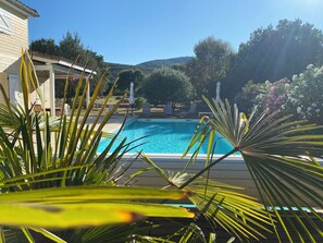 A swimming pool with a view of a house and trees in the background.