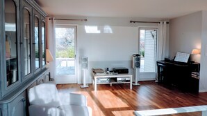 A room with a piano, a white armchair, a glass coffee table, and a cabinet with glass doors.