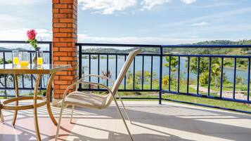 Un balcon avec une table, des chaises et une vue sur un lac.