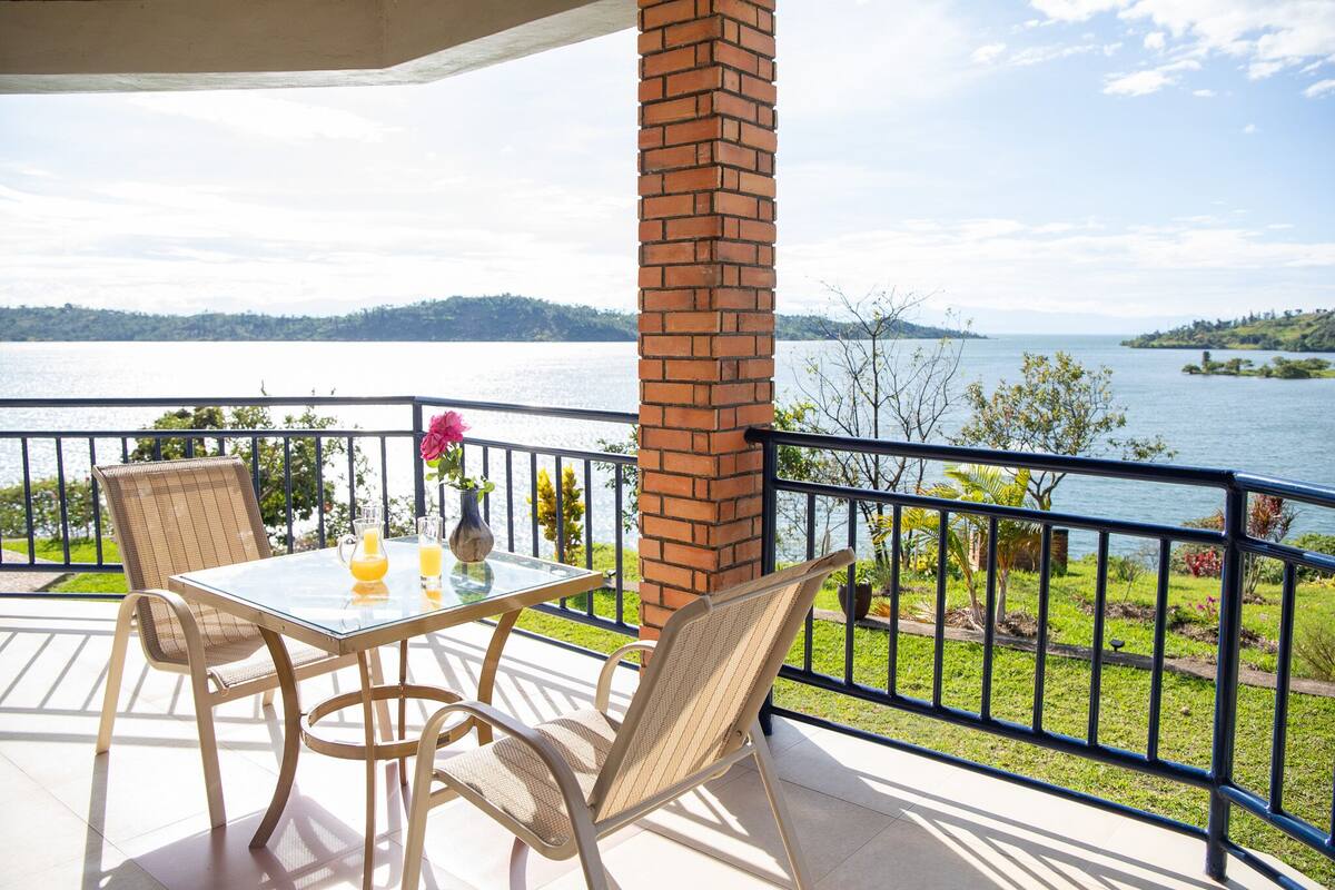 Un balcon avec une table, des chaises et une vue sur un lac.